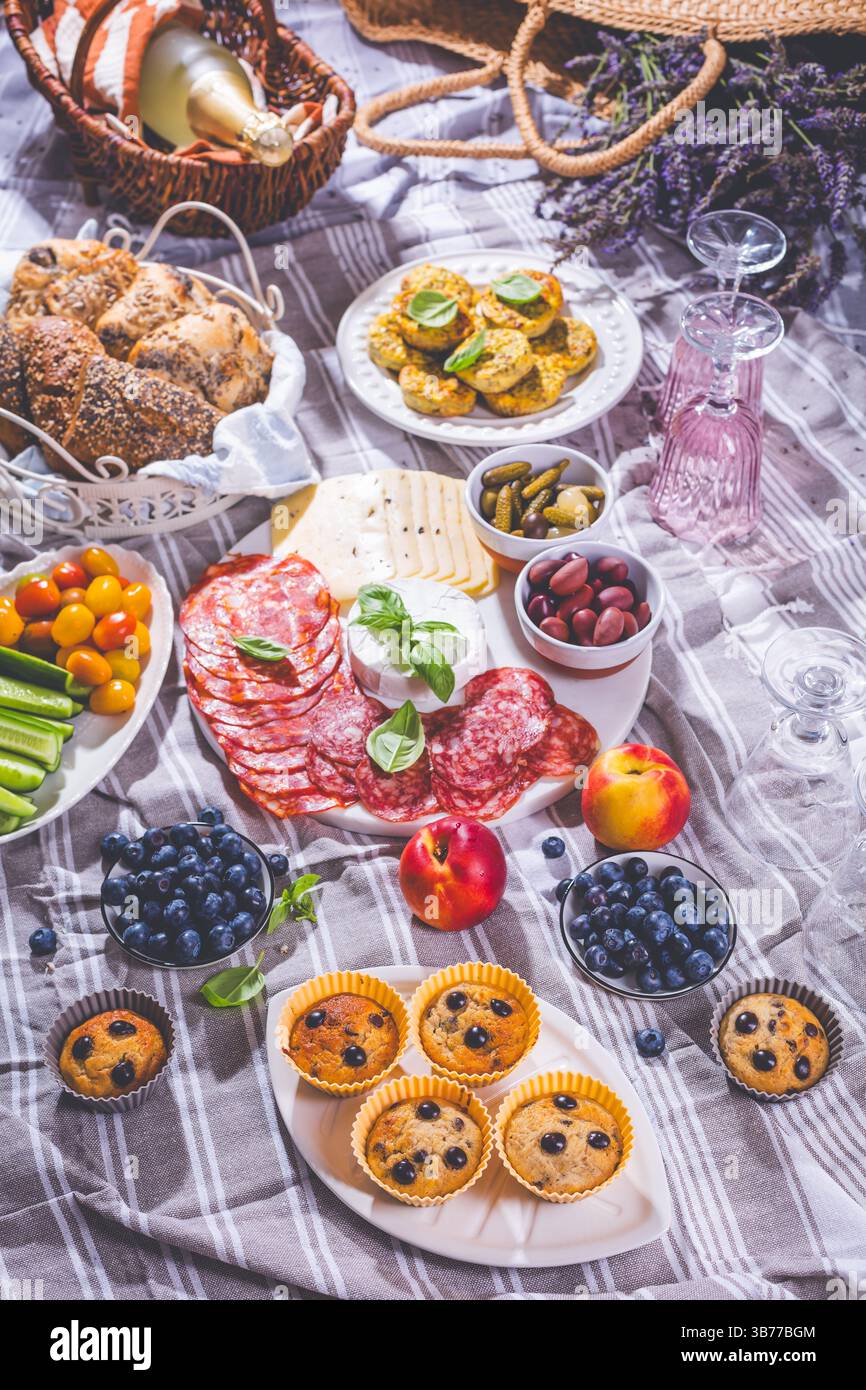 Picnic, antipasti e vassoio di formaggi e carne con muffin dolci e salati e frutta Foto Stock