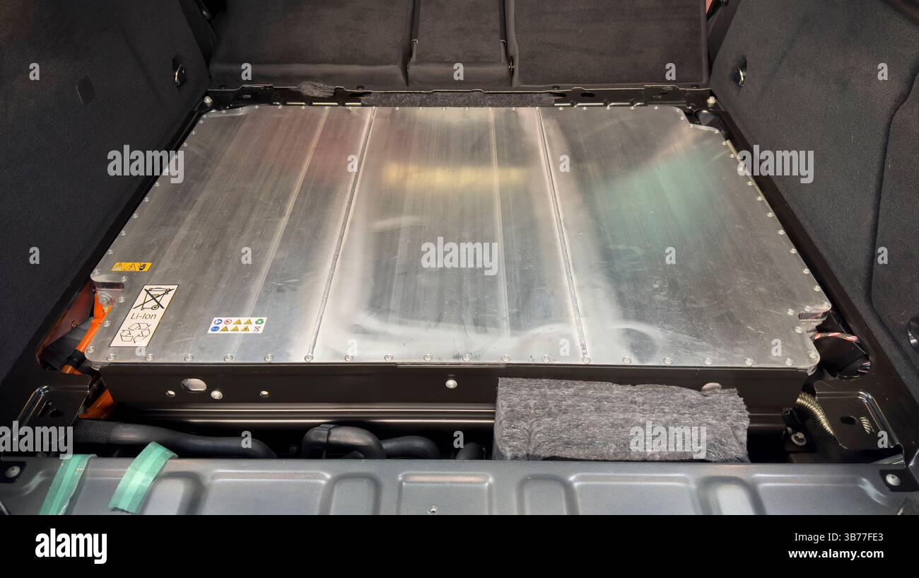 Una batteria per auto elettriche con etichette di avvertenza visibili, simboli di riciclaggio e involucro in metallo. Foto Stock