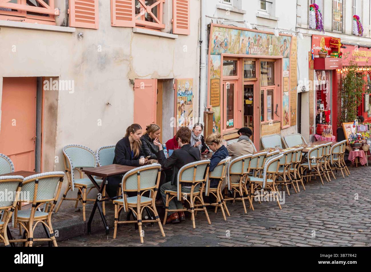 Giovani donne sedute all'aperto del ristorante le Poulbot al 3 Rue Poulbot nel quartiere Montmartre di Parigi, Francia Foto Stock
