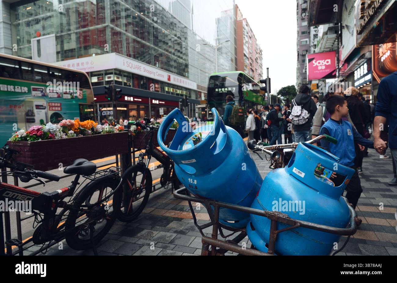 Taniche di gas blu, biciclette, fioriere floreali e centri commerciali in vetro a Tsim Sha Tsui Foto Stock