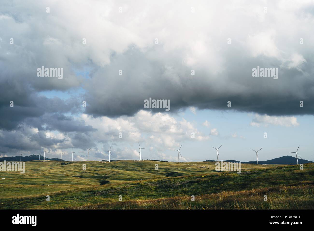 Panorama di molte enormi turbine eoliche sulla linea dell'orizzonte con cielo blu con nuvole. Concetto di tecnologia ecocompatibile. Parco eolico industriale nel nord di Monteneg Foto Stock