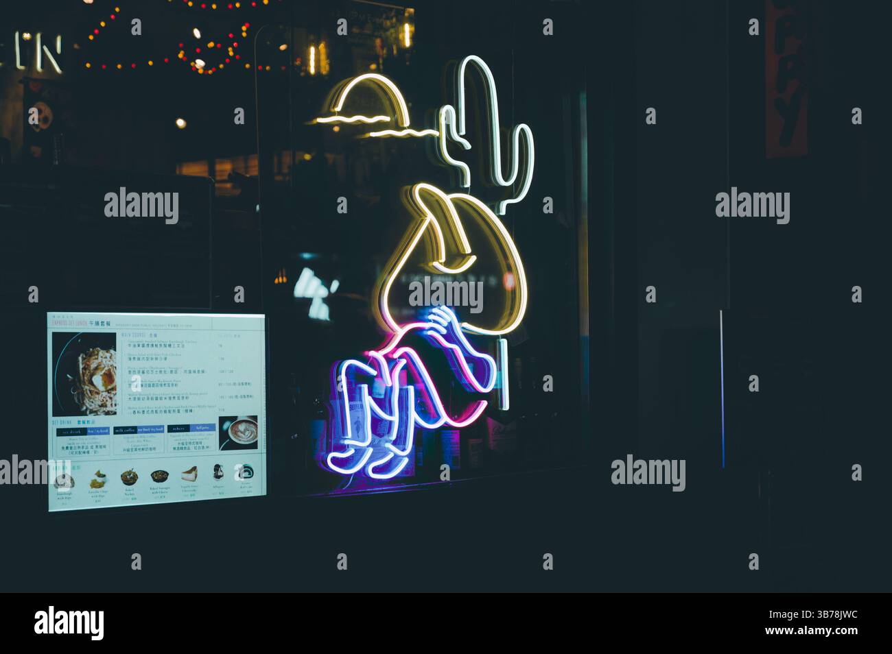 Cactus giocosi e figura rilassata illuminano la notte fuori da un ristorante messicano Foto Stock