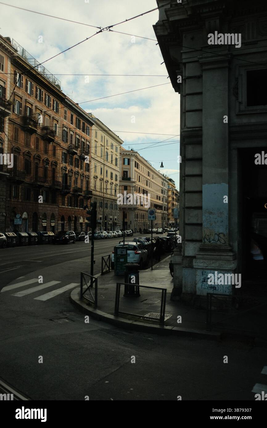 Intersezione stradale nel centro di Roma con la classica architettura europea edifici storici linee di tram e auto parcheggiate sotto il cielo nuvoloso scenario di viaggio urbano. Foto di alta qualità Foto Stock