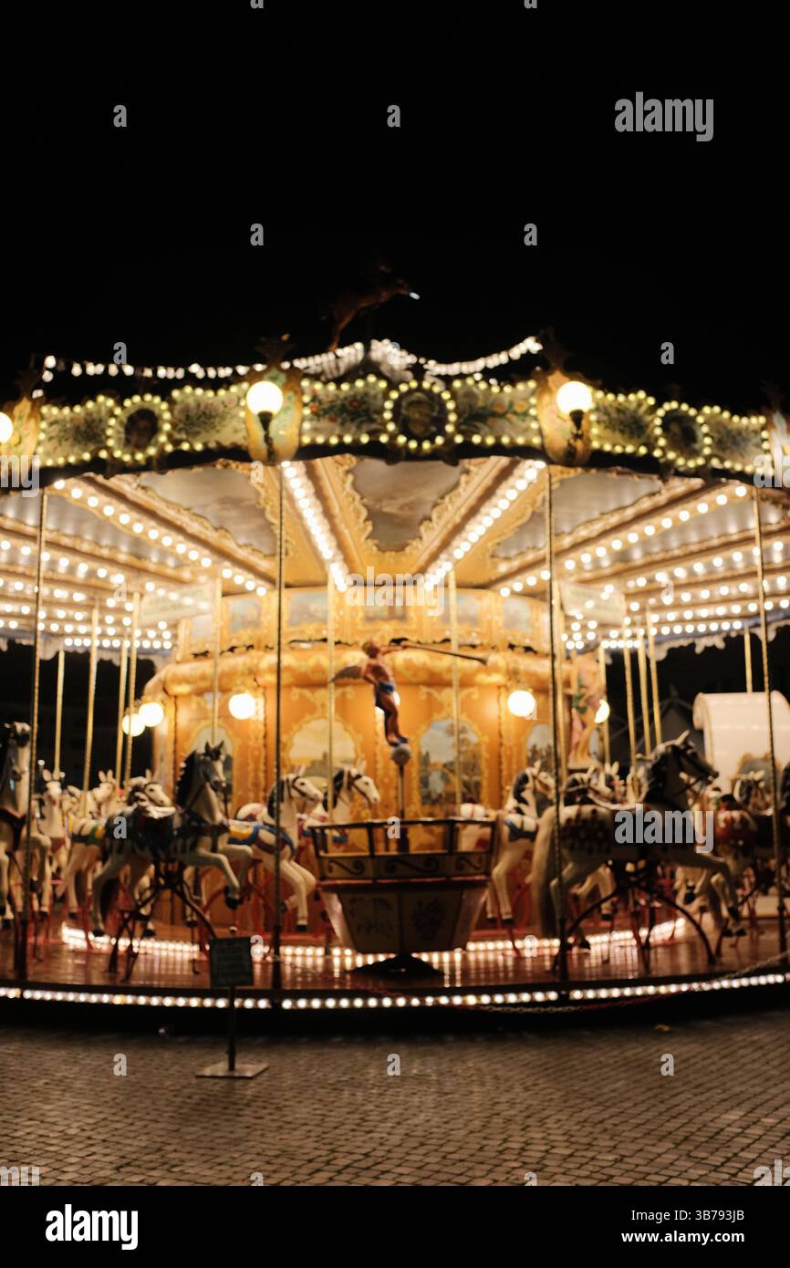 Giostra d'epoca luminosa che gira di notte in Piazza Navona a Roma con decorazioni festose e un'atmosfera festosa. Foto di alta qualità Foto Stock