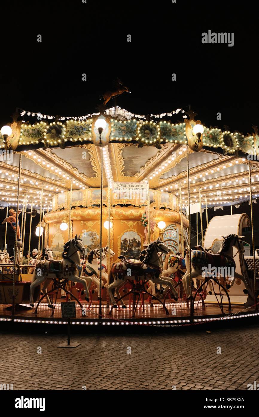 Giostra d'epoca luminosa che gira di notte in Piazza Navona a Roma con decorazioni festose e un'atmosfera festosa. Foto di alta qualità Foto Stock