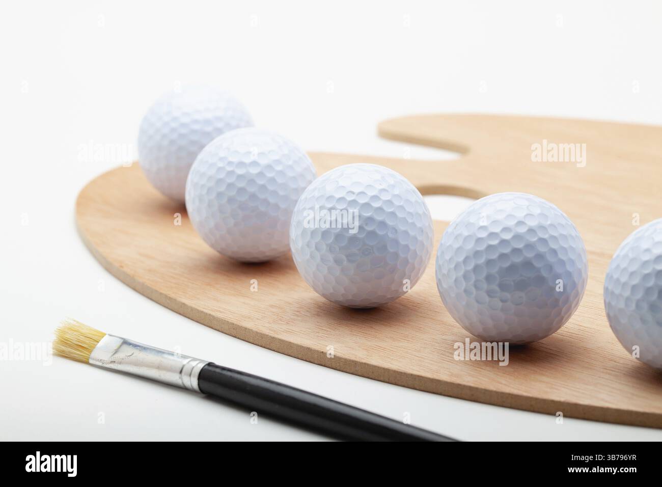 Pulire la tavolozza delle opere d'arte in legno con una palla da golf bianca e una spazzola isolata su sfondo bianco Foto Stock