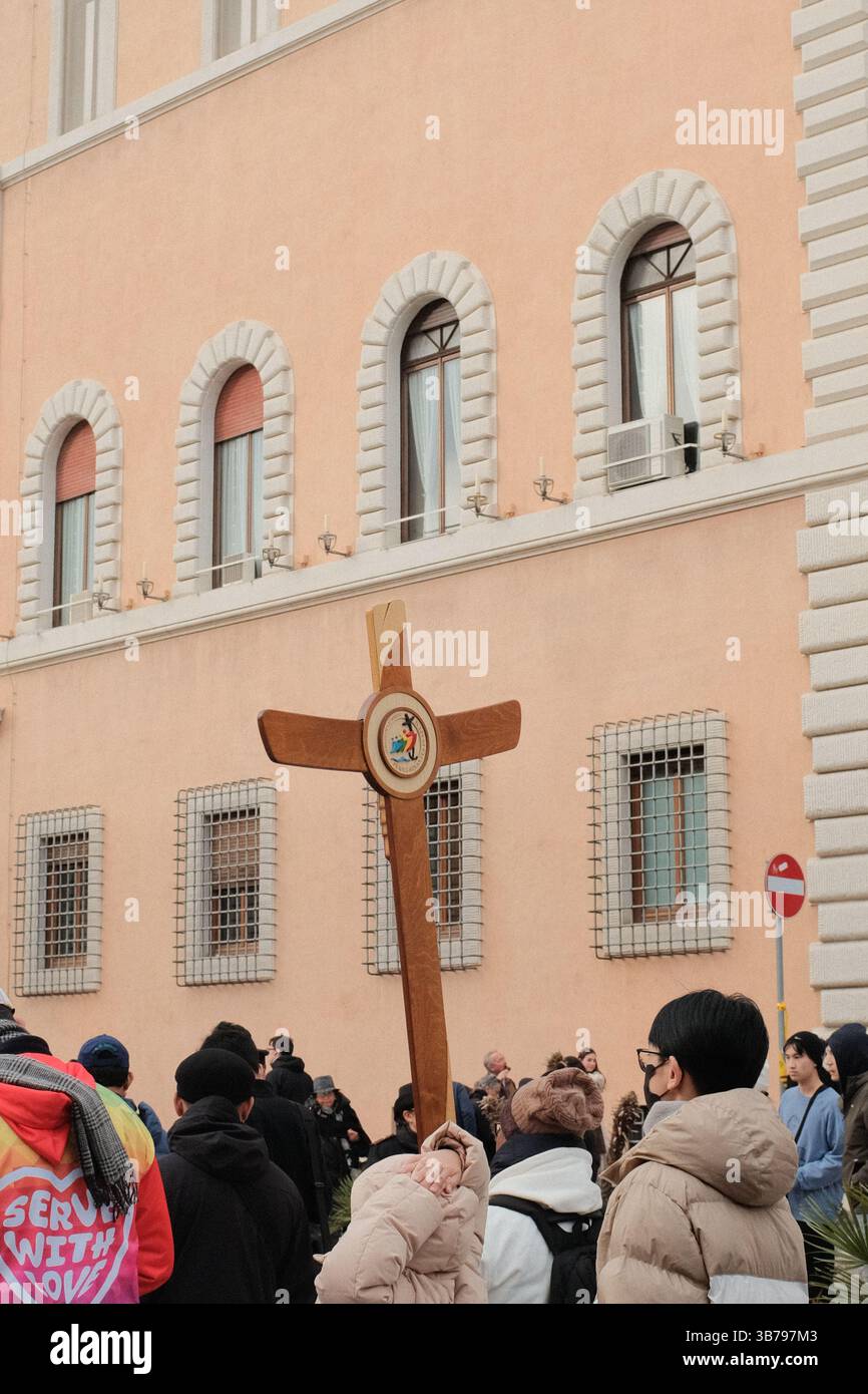 Processione religiosa a Roma con un gruppo di pellegrini che trasportano una grande croce di legno attraverso la storica strada durante il Giubileo dei pellegrini della speranza di Roma 2025 Foto Stock
