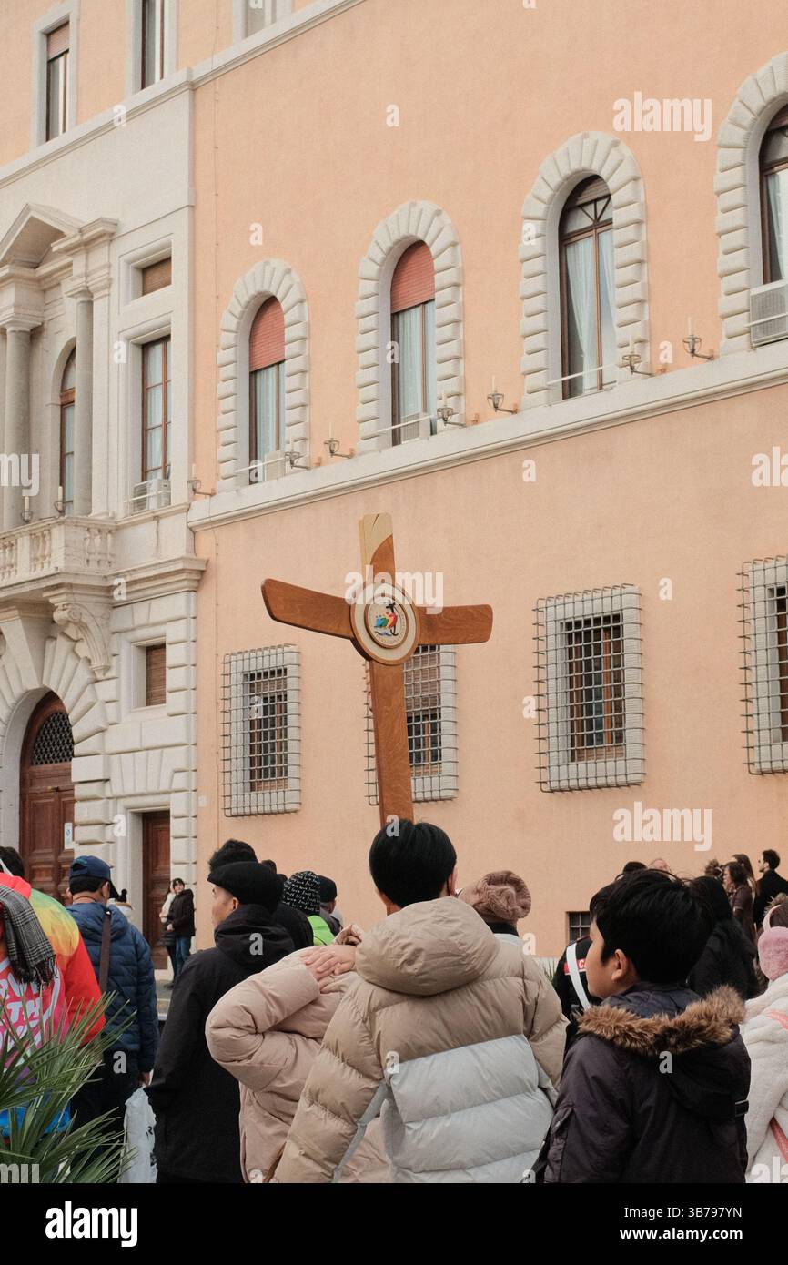 Processione religiosa a Roma con un gruppo di pellegrini che trasportano una grande croce di legno attraverso la storica strada durante il Giubileo dei pellegrini della speranza di Roma 2025 Foto Stock