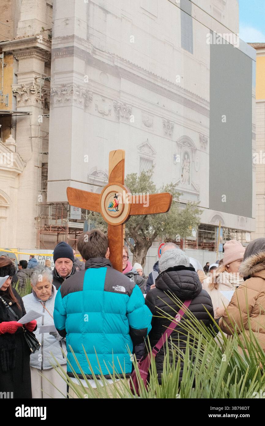 Processione religiosa a Roma con un gruppo di pellegrini che trasportano una grande croce di legno attraverso la storica strada durante il Giubileo dei pellegrini della speranza di Roma 2025 Foto Stock