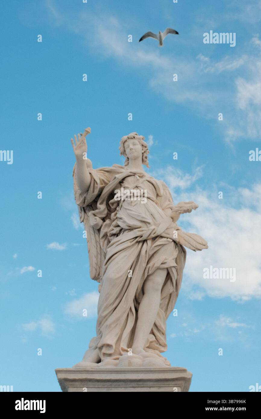 Statue d'angelo barocco sul Ponte Sant'Angelo a Roma con un cielo spettacolare e la classica architettura romana sullo sfondo, monumento culturale e dettagli scultorei. Foto di alta qualità Foto Stock