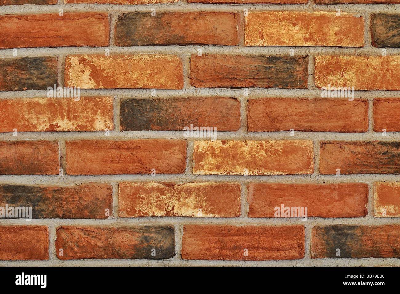 Primo piano autentico di una parete rustica in mattoni rossi che mostra variazioni di colore naturali e texture grintose; sfondo perfetto o elemento di design. Foto Stock