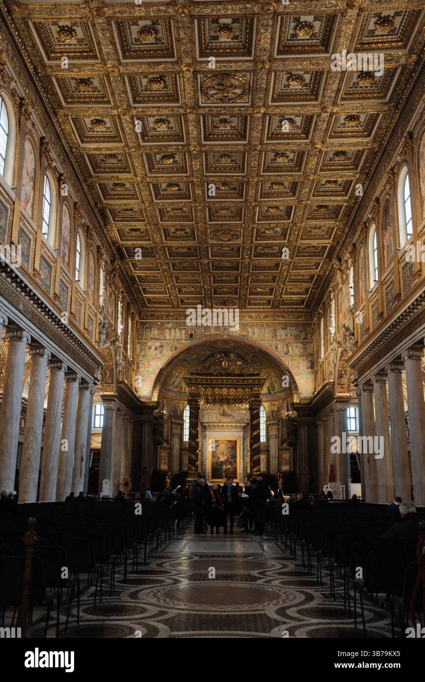 Soffitto decorato a cassettoni dorati e interni riccamente decorati della Basilica di Santa Maria maggiore a Roma, Italia, con file di pali, pavimento in marmo e altare illuminato all'estremità Foto di alta qualità Foto Stock
