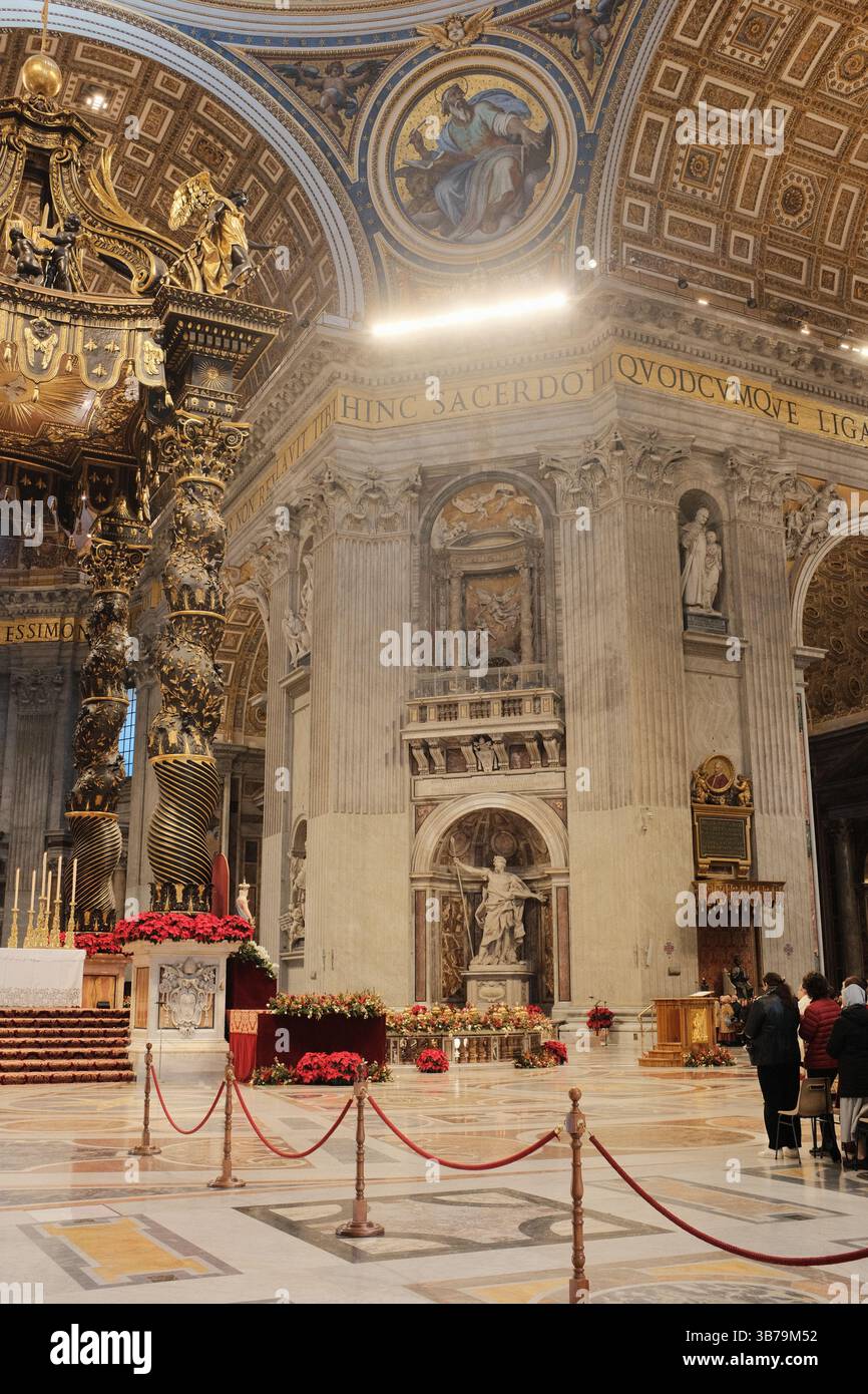 Baldacchino ornato sull'altare papale nella Basilica di San Pietro città del Vaticano progettato da Gian Lorenzo Bernini con colonne in bronzo ritorto decorazioni floreali rosse e iscrizioni latine sotto la grande cupola. Foto di alta qualità Foto Stock