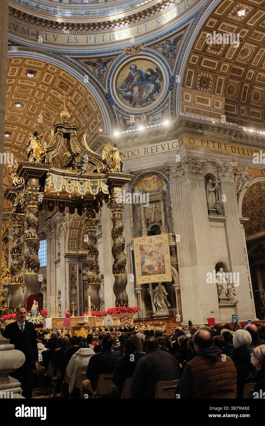 Baldacchino ornato sull'altare papale nella Basilica di San Pietro città del Vaticano progettato da Gian Lorenzo Bernini con colonne in bronzo ritorto decorazioni floreali rosse e iscrizioni latine sotto la grande cupola. Foto di alta qualità Foto Stock