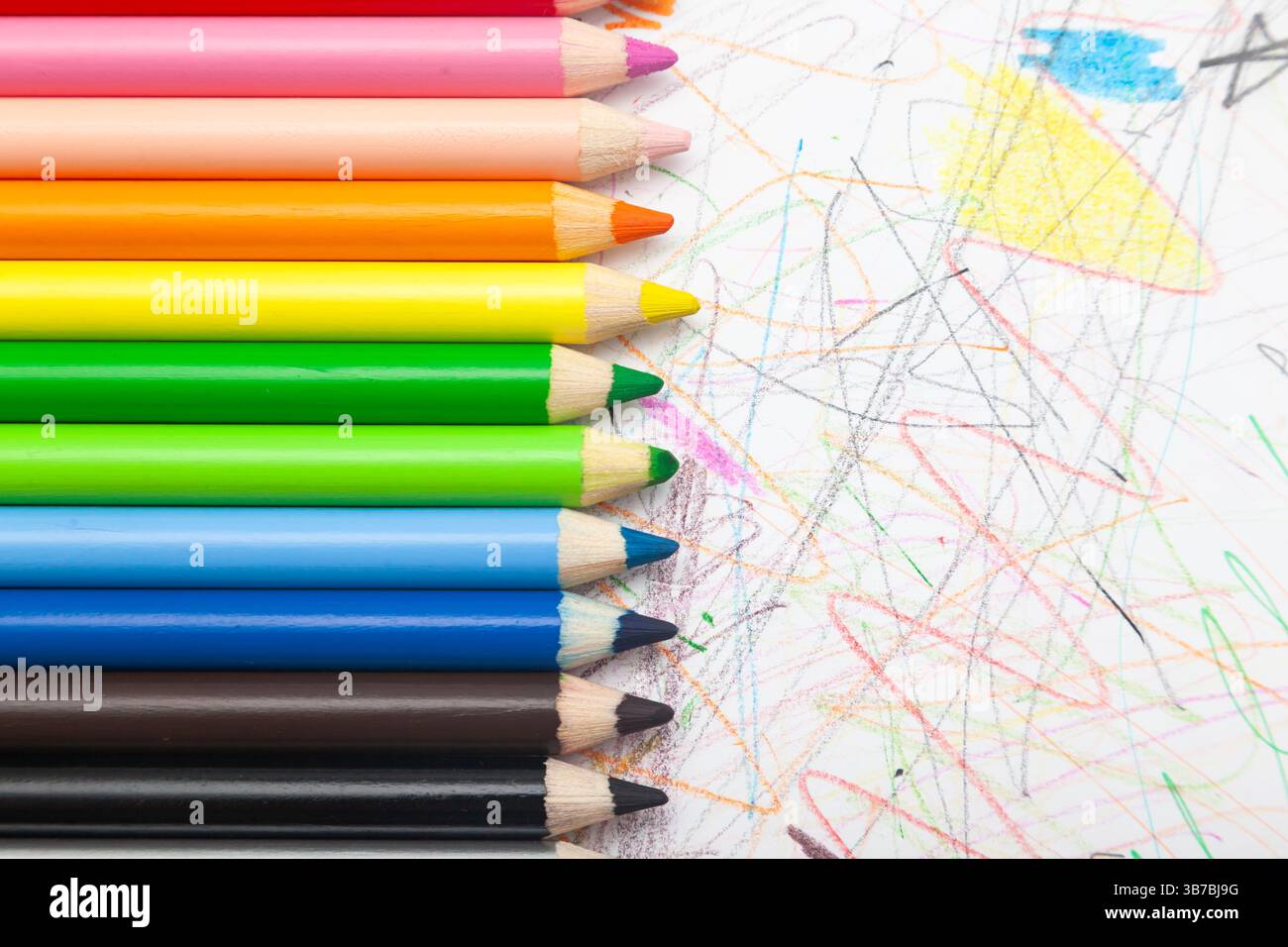Le matite multicolore si trovano su carta bianca disegnata con linee ricurve multicolore. Foto Stock
