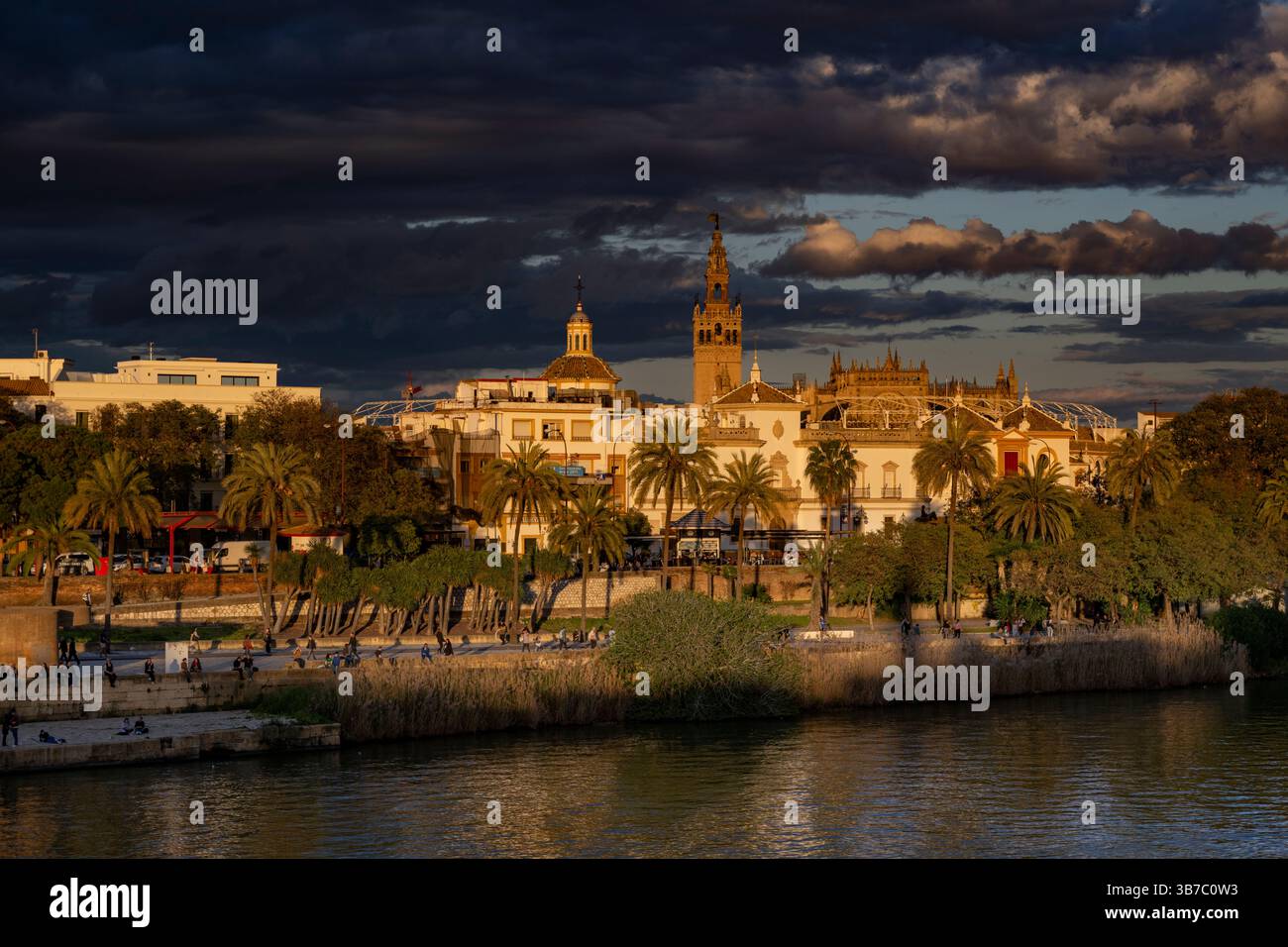 Vista sul fiume Guadalquivir al tramonto. Sullo sfondo si trova la torre della Giralda e la cattedrale di Siviglia. Andalusia, Spagna Foto Stock