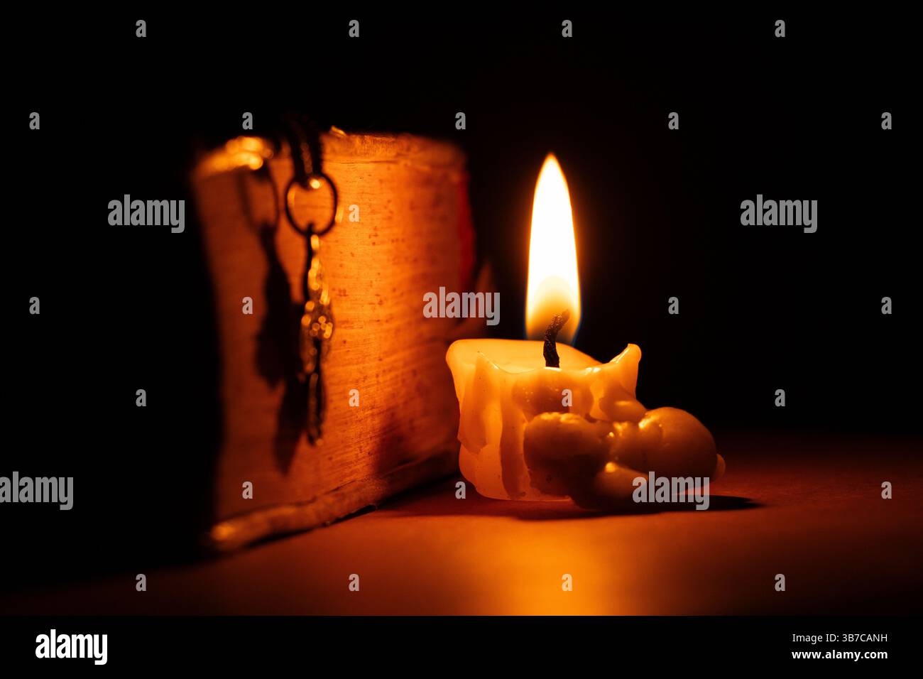 Candele accese, croce e Bibbia giacciono sul tavolo nel buio, nelle candele e nella Bibbia Foto Stock