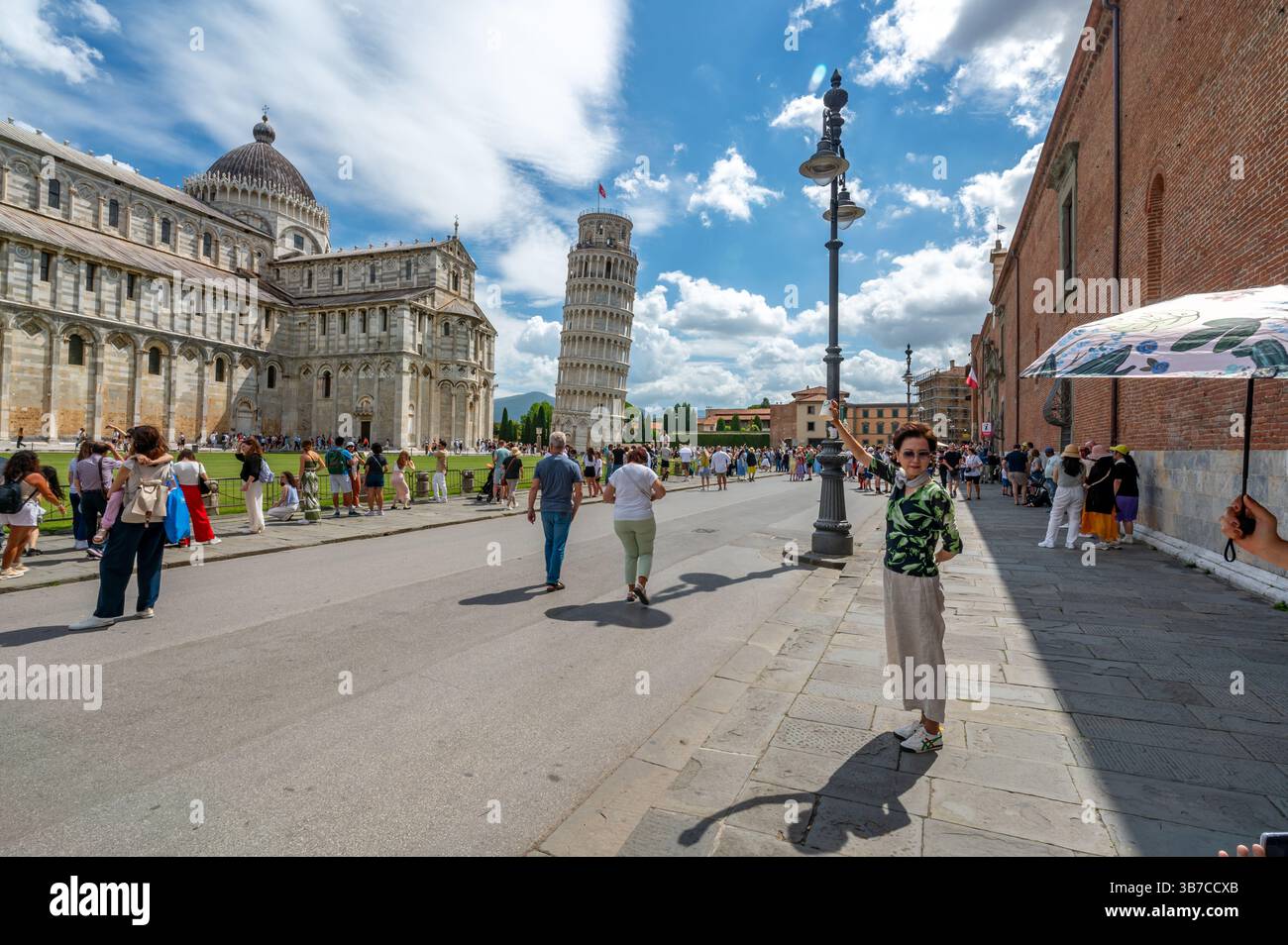 Pisa, Italia - 12.6,2024: I turisti che posano di fronte alla Torre pendente di Pisa (Torre pendente di Pisa), usando la prospettiva forzata per apparire come se fossero in attesa Foto Stock