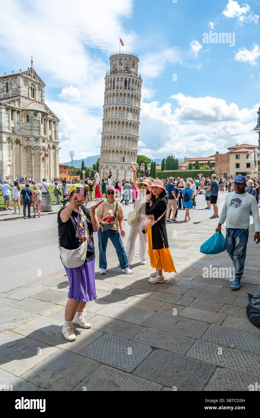 Pisa, Italia - 12.6,2024: I turisti che posano di fronte alla Torre pendente di Pisa (Torre pendente di Pisa), usando la prospettiva forzata per apparire come se fossero in attesa Foto Stock