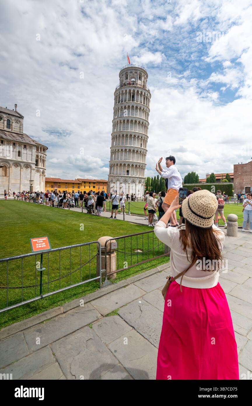 Pisa, Italia - 12.6,2024: I turisti che posano di fronte alla Torre pendente di Pisa (Torre pendente di Pisa), usando la prospettiva forzata per apparire come se fossero in attesa Foto Stock