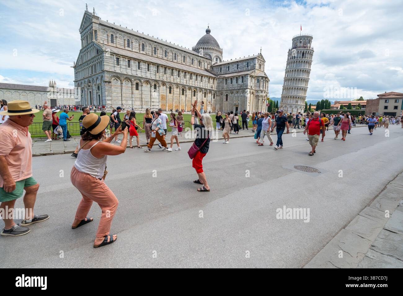 Pisa, Italia - 12.6,2024: I turisti che posano di fronte alla Torre pendente di Pisa (Torre pendente di Pisa), usando la prospettiva forzata per apparire come se fossero in attesa Foto Stock