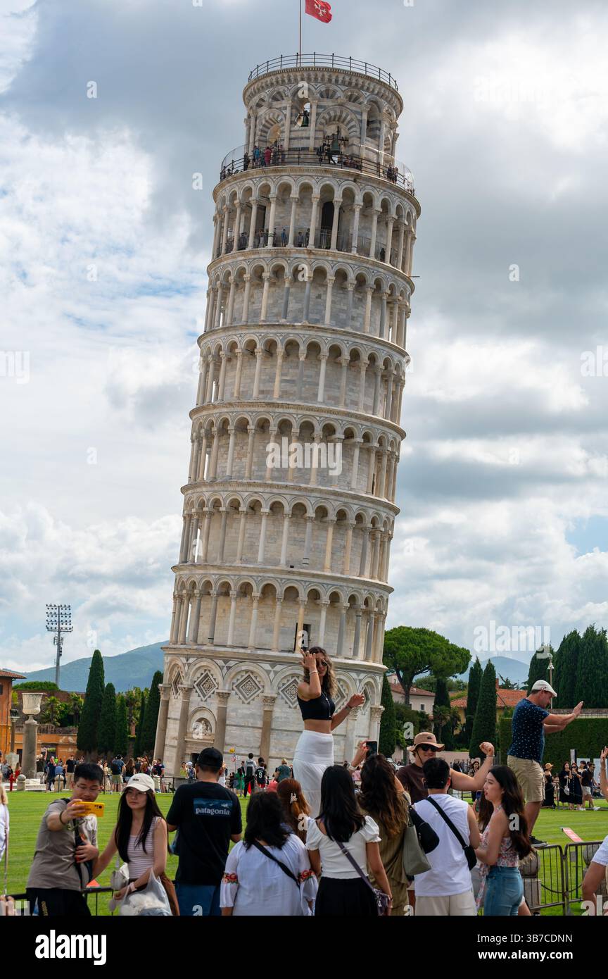 Pisa, Italia - 12.6,2024: I turisti che posano di fronte alla Torre pendente di Pisa (Torre pendente di Pisa), usando la prospettiva forzata per apparire come se fossero in attesa Foto Stock