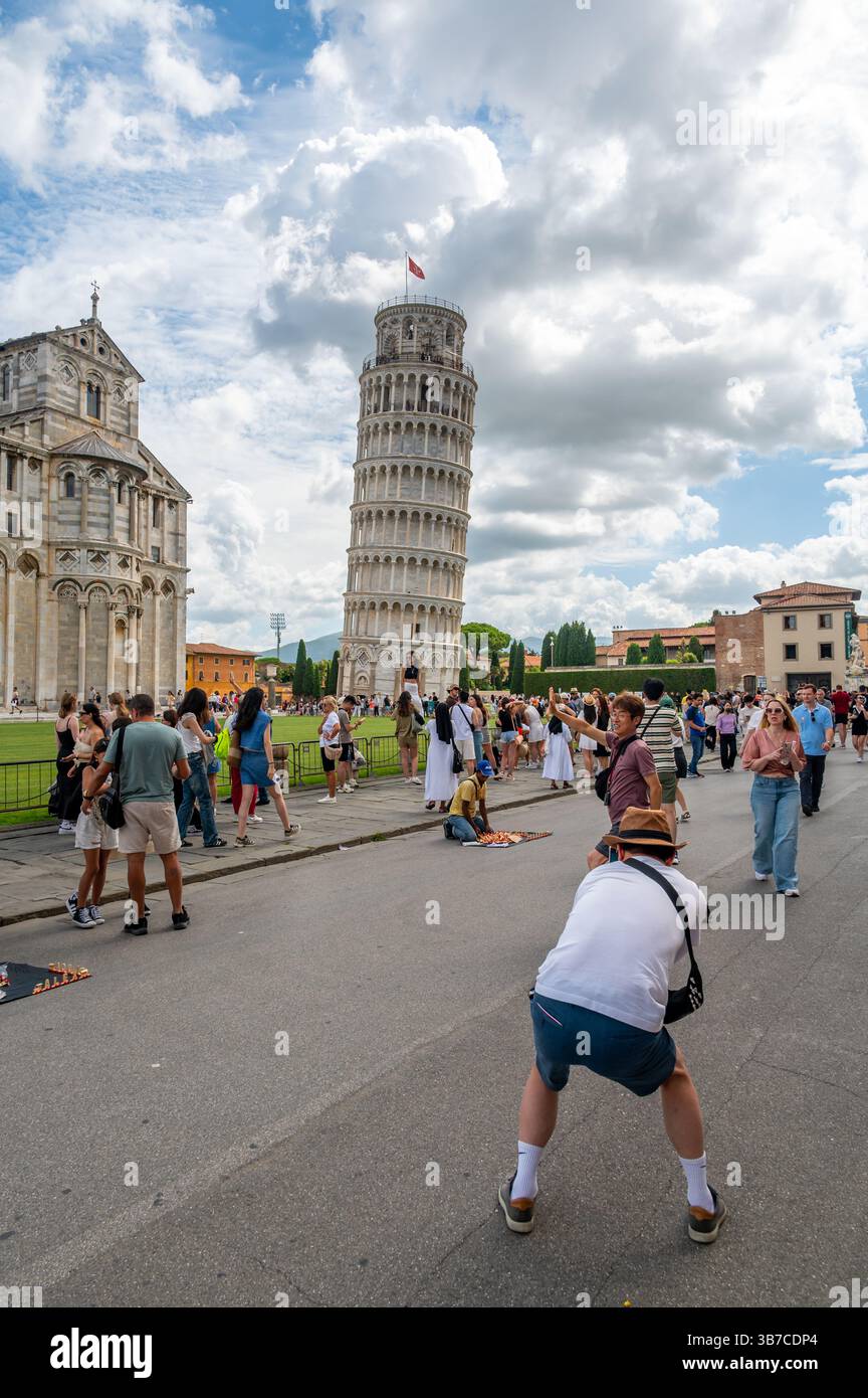 Pisa, Italia - 12.6,2024: I turisti che posano di fronte alla Torre pendente di Pisa (Torre pendente di Pisa), usando la prospettiva forzata per apparire come se fossero in attesa Foto Stock