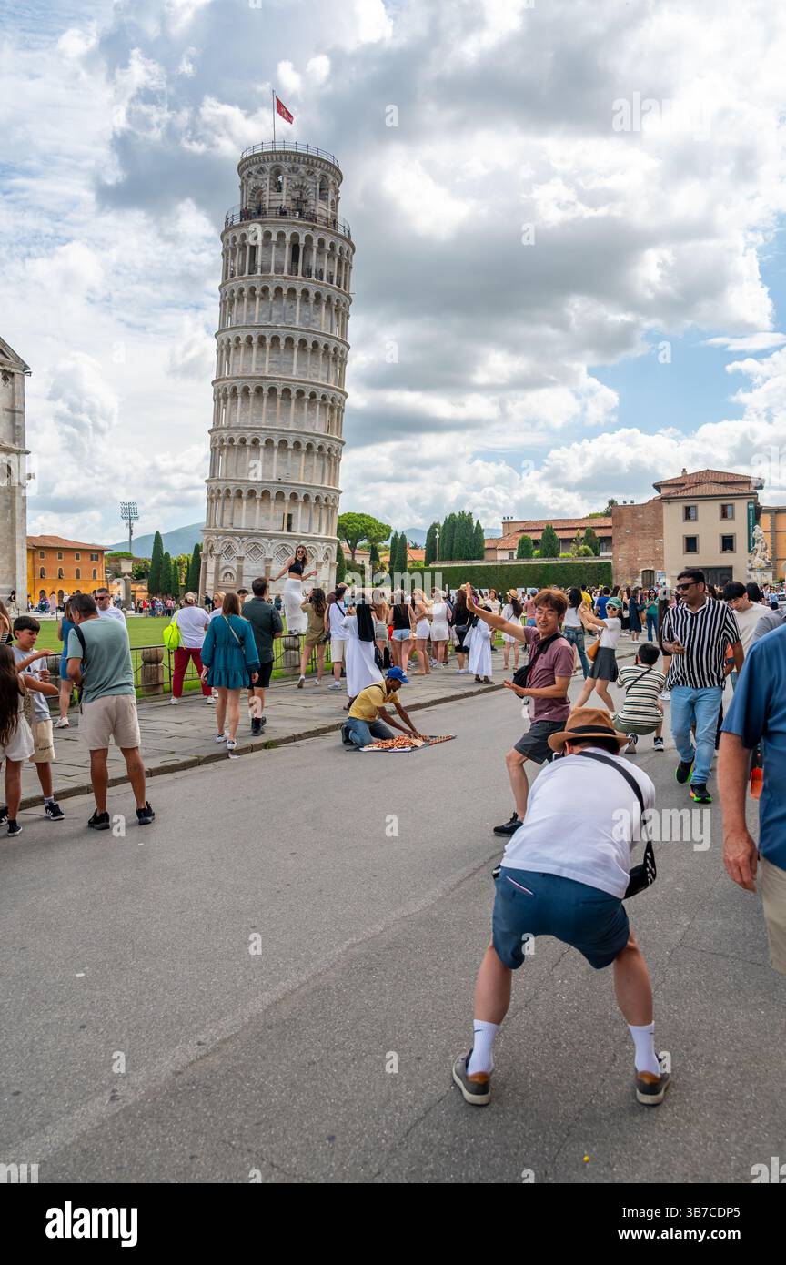 Pisa, Italia - 12.6,2024: I turisti che posano di fronte alla Torre pendente di Pisa (Torre pendente di Pisa), usando la prospettiva forzata per apparire come se fossero in attesa Foto Stock