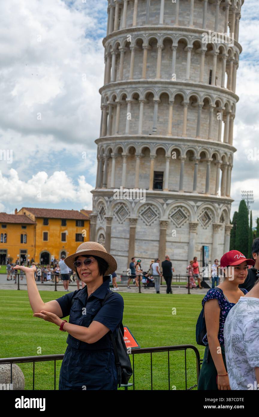 Pisa, Italia - 12.6,2024: I turisti che posano di fronte alla Torre pendente di Pisa (Torre pendente di Pisa), usando la prospettiva forzata per apparire come se fossero in attesa Foto Stock