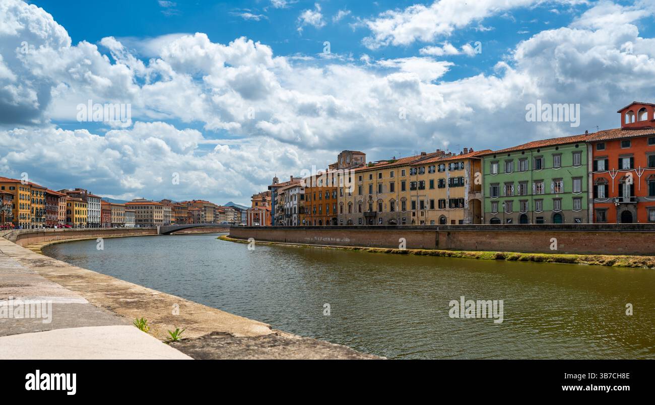 Centro città di Pisa, Italia, con il fiume Arno che scorre attraverso. Colorati edifici lungo il fiume fiancheggiano le rive sotto i luminosi cieli estivi in un caldo Medit Foto Stock