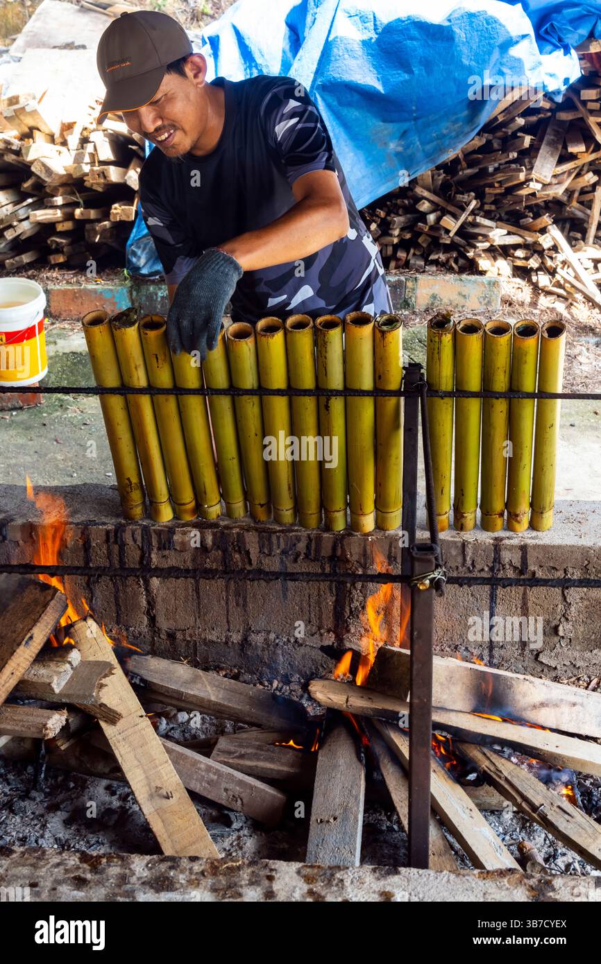 Uomo malese che cucina riso in tubo di bambù. Si chiama anche riso di bambù o riso di bambù fragrante, Malesia. La morbidezza e la freschezza del torrefatto Foto Stock