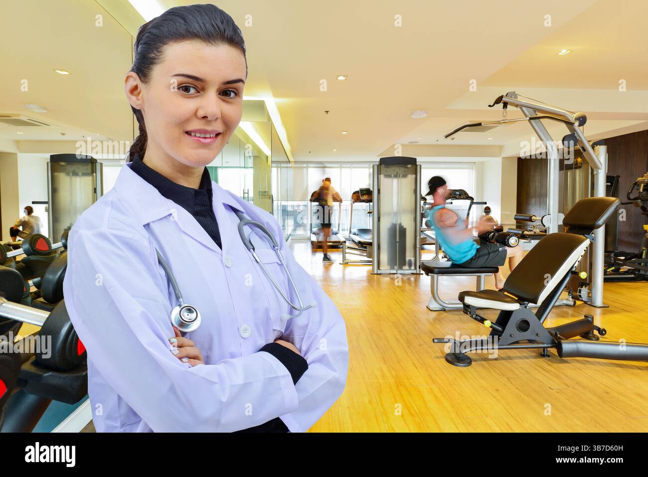 Bellissimo giovane medico con stetoscopio sullo sfondo della sala fitness. concetto di fitness sano per le persone Foto Stock