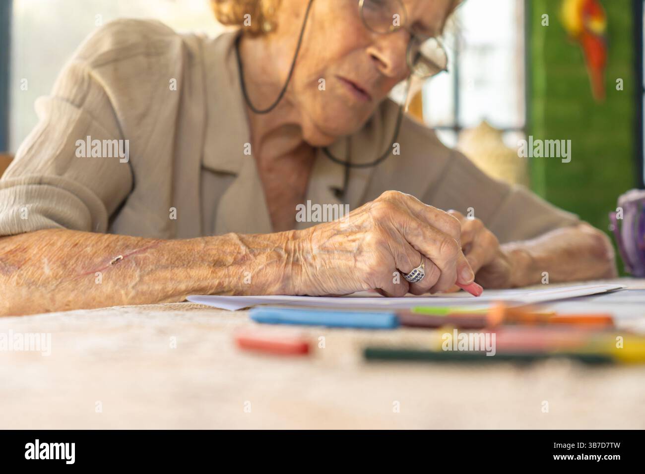 Donna anziana che ama l'arte terapeutica a casa, disegna con pastelli vivaci, abbraccia il relax e l'espressione creativa attraverso le sue attività artistiche Foto Stock