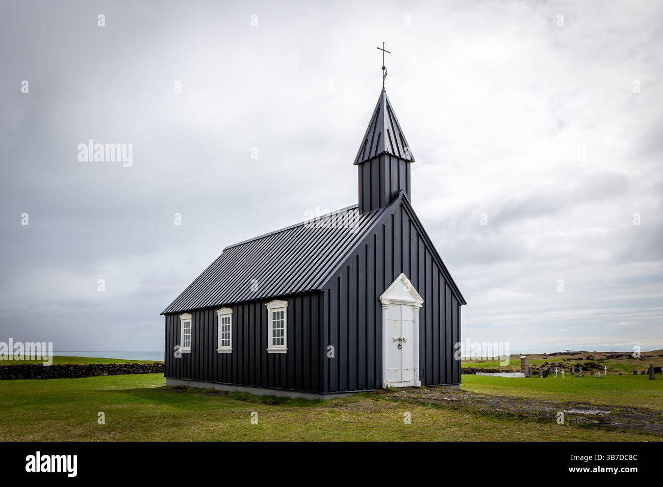 Budakirkja Church (Chiesa Nera d'Islanda) sulla penisola di Snaefellsnes, Islanda, con erba verde e cielo nuvoloso. Foto Stock