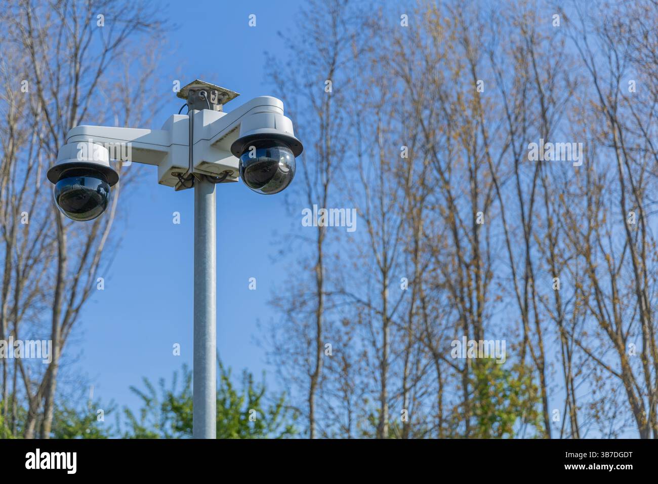 Due telecamere di sicurezza sono montate su un palo, che sorvegliano l'area sotto un cielo limpido Foto Stock