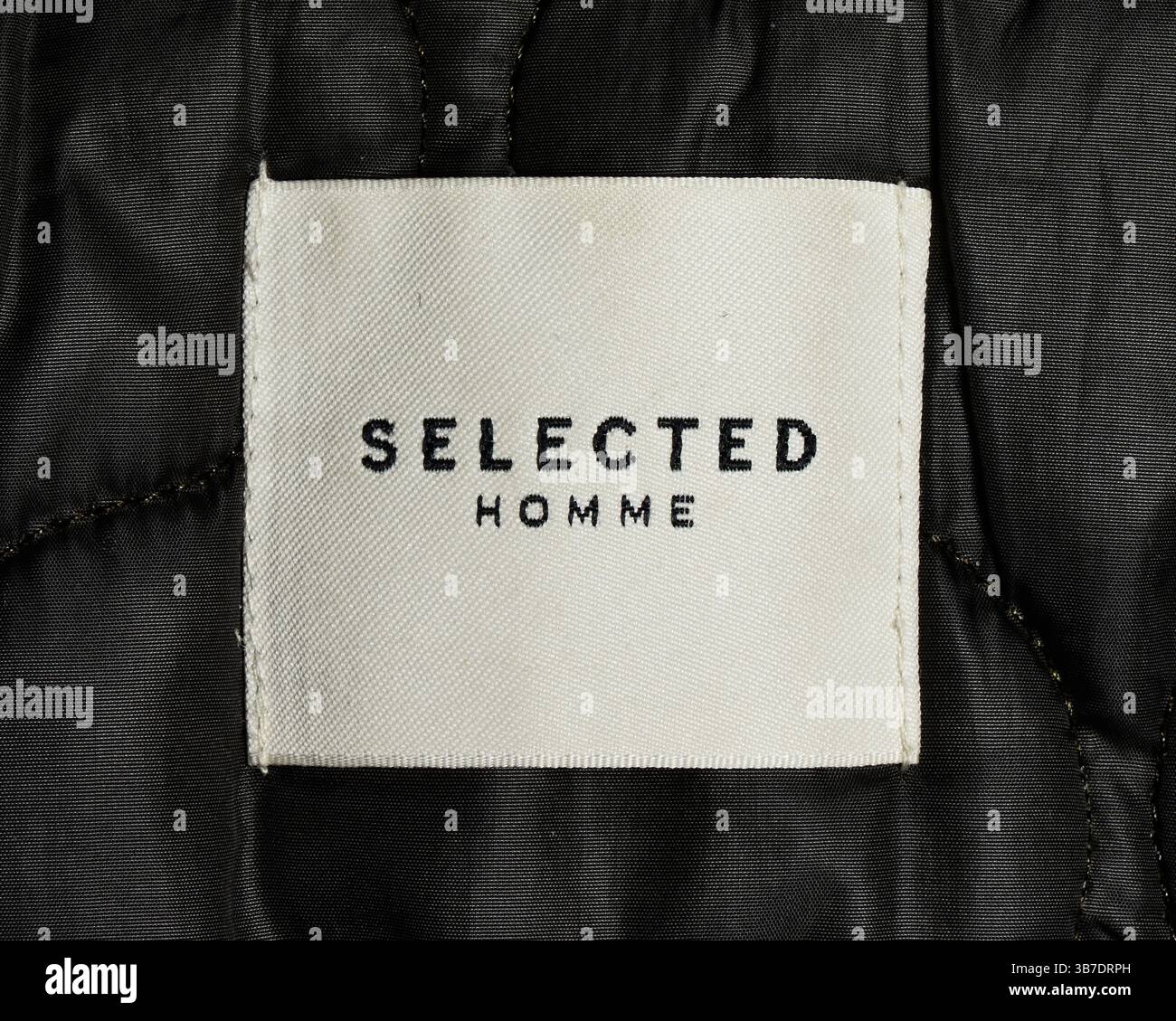 Etichetta Homme selezionata cucita su una giacca, che mostra i dettagli del marchio sugli outerwear della moda maschile contemporanea Foto Stock