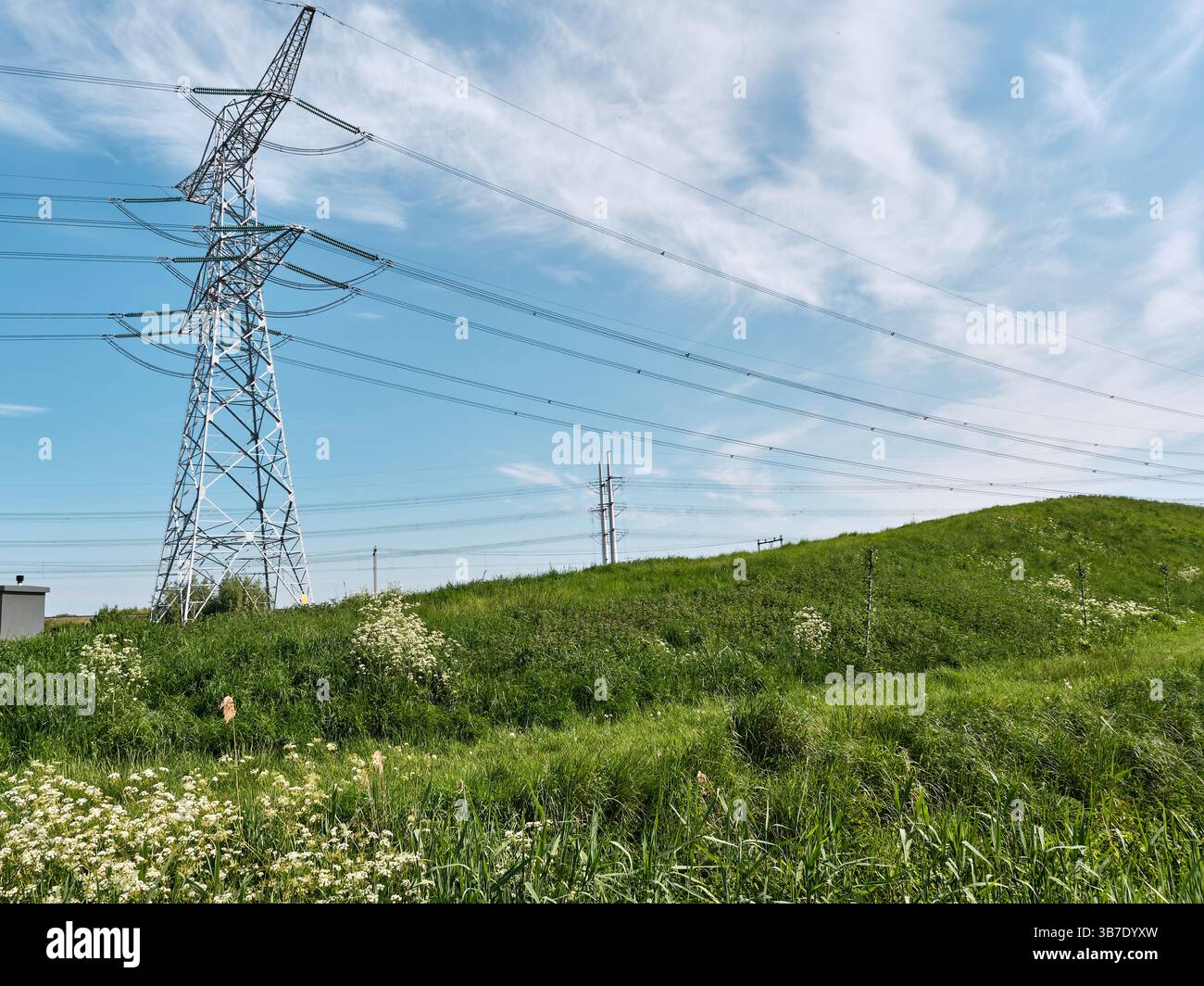 3 maggio 2025 - Kruiningen-Paesi Bassi: Paesaggio energetico rurale in Zelanda con torre Powerline da 150 kV e una vecchia diga ripida vicino a Kruiningen. Foto Stock
