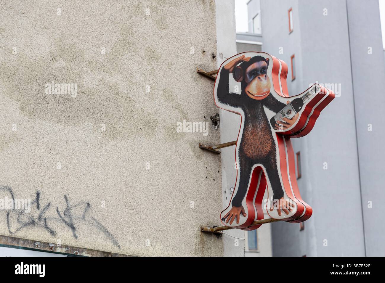 Un stravagante e cartoni animati insegna scimmia, che tiene una bottiglia di birra e la graffia la testa, è montato sull'esterno di un edificio intempestivo. Berlino, Germania. 30 Marc Foto Stock