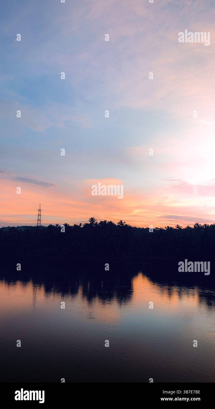 tramonto su un lago tranquillo con riflessi colorati. e serate tranquille sul lago con un cielo panoramico - Immagine stock catturata con smartphone