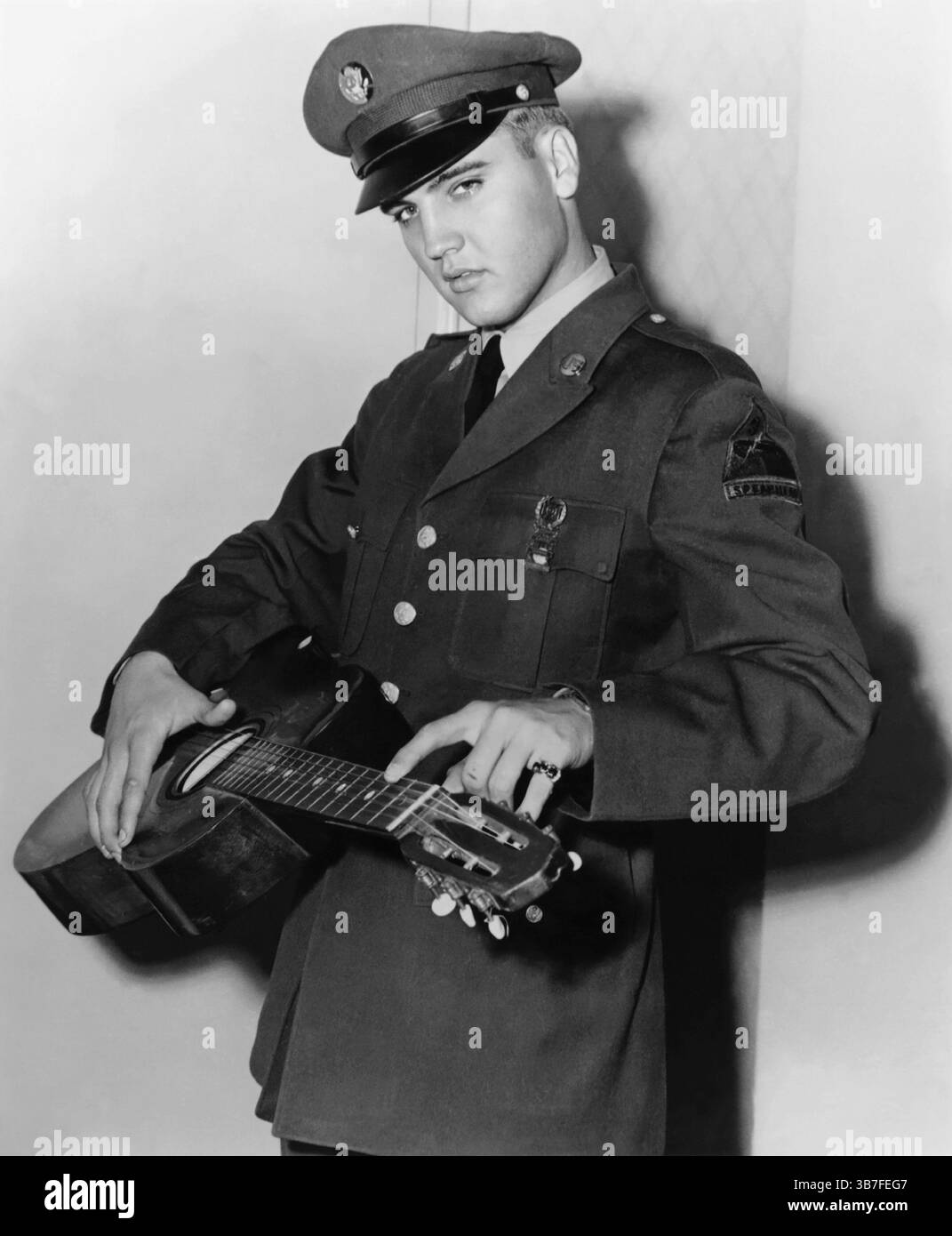 La leggenda del rock and roll Elvis Presley in uniforme con una chitarra durante il suo periodo di servizio militare in Germania, intorno al 1959 Foto Stock
