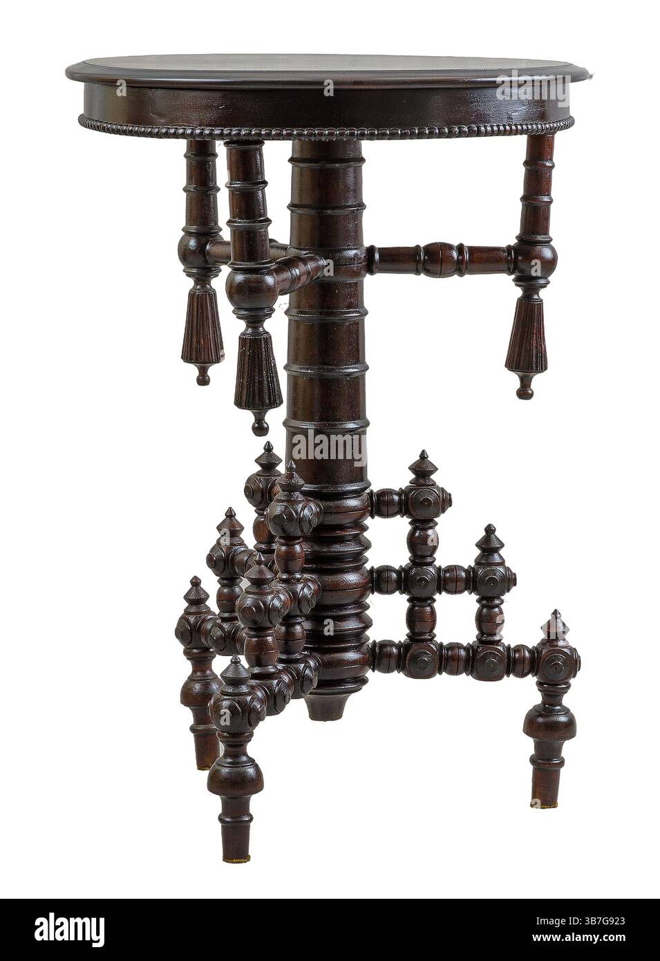 Un tavolino in legno vintage presenta un piano circolare e dettagliate incisioni sulle gambe. Il tavolo si trova in una sala illuminata con luce soffusa, aggiungendo un tocco di eleganza Foto Stock