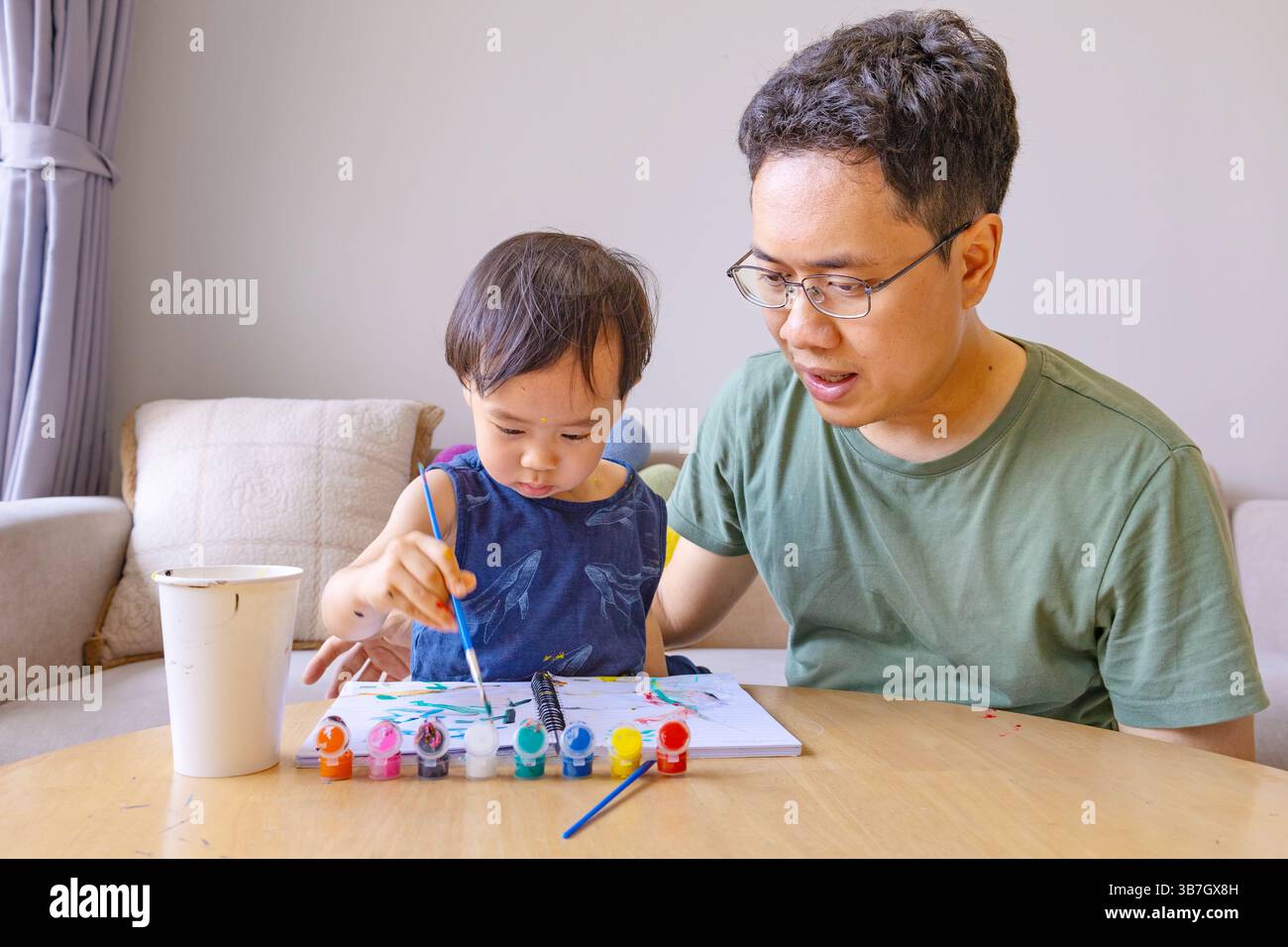 Un padre guida pazientemente il suo bambino attraverso una sessione di pittura creativa, il potere del coinvolgimento dei genitori nell'educazione della prima infanzia. Materiale fotografico Foto Stock