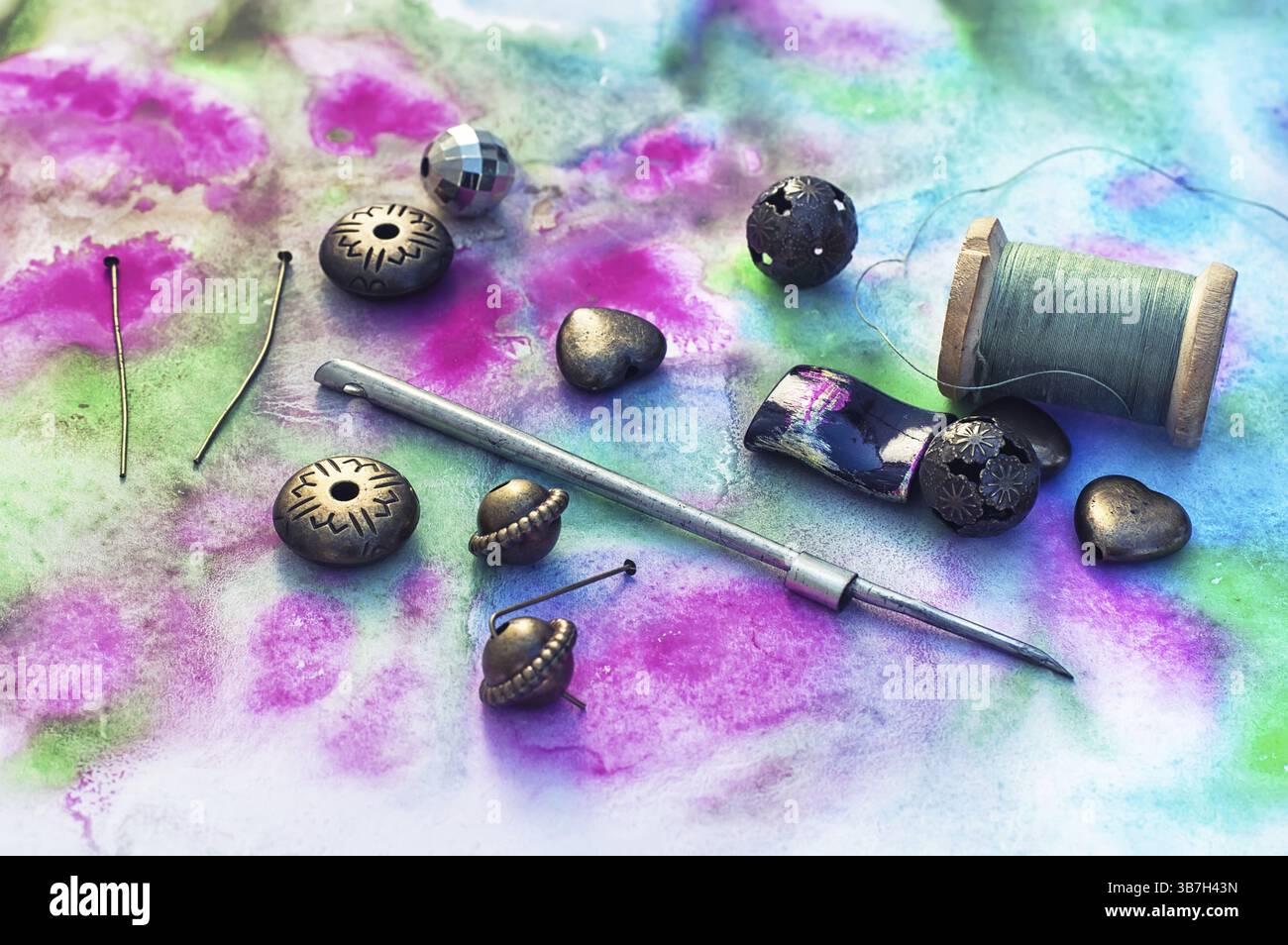 Perle e strumenti per il lavoro di ricamo su sfondo lucido Foto Stock