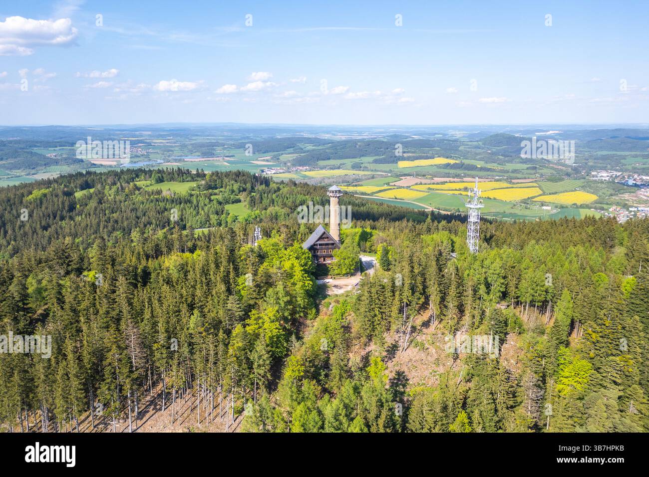 Questa vista aerea cattura la torre di osservazione di Svatobor circondata da foreste lussureggianti e colline ondulate in Cechia in una giornata limpida. I visitatori possono ammirare paesaggi mozzafiato da questo punto panoramico. Foto Stock