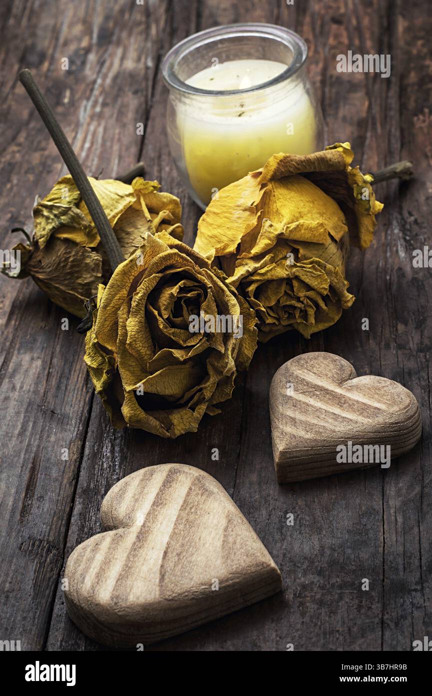 Cuore simbolico in legno intagliato a mano sullo sfondo di rose gialle Foto Stock