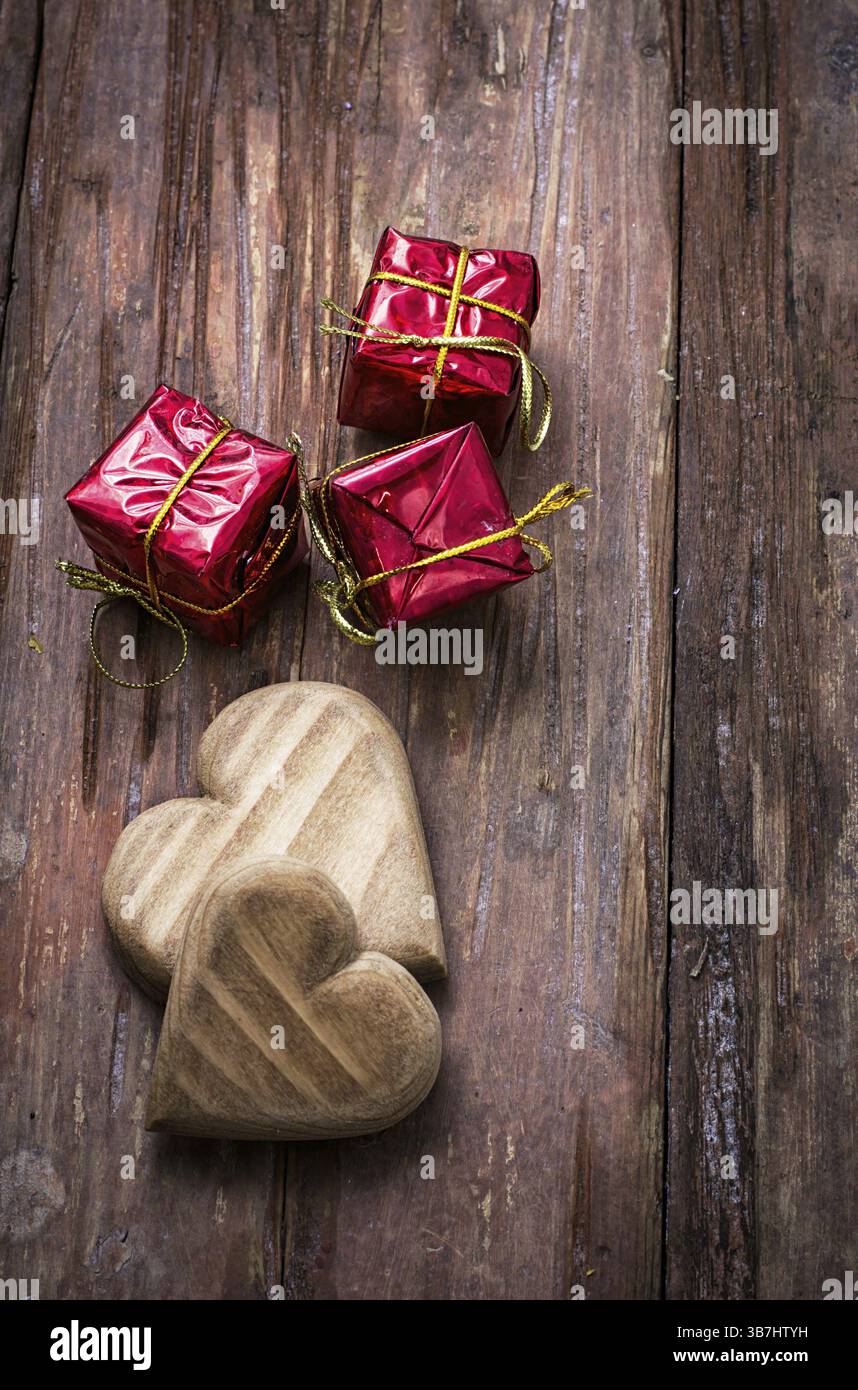 Cuore simbolico in legno intagliato a mano su uno sfondo di rose gialle Foto Stock