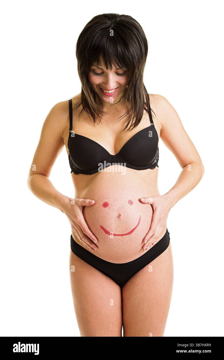 Donna felice incinta con un viso divertente sorridente dipinto sulla pancia Foto Stock