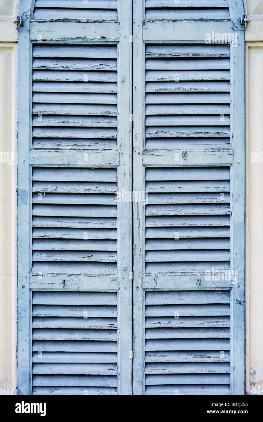 Vecchie persiane blu sulla parete luminosa della casa. Foto Stock