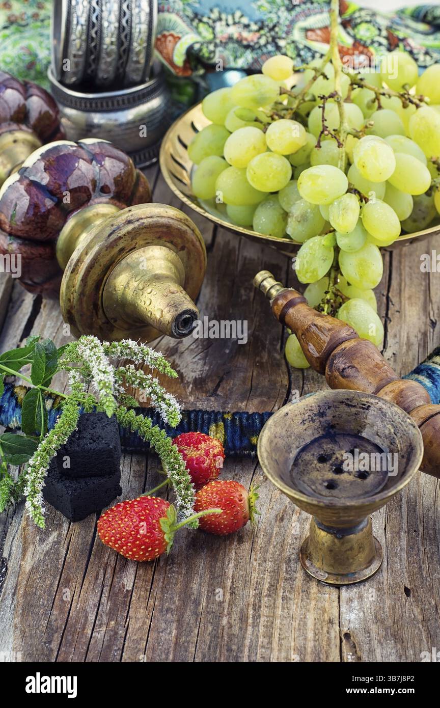 Hookah con sapore di frutta sul tavolo in legno in stile vintage Foto Stock