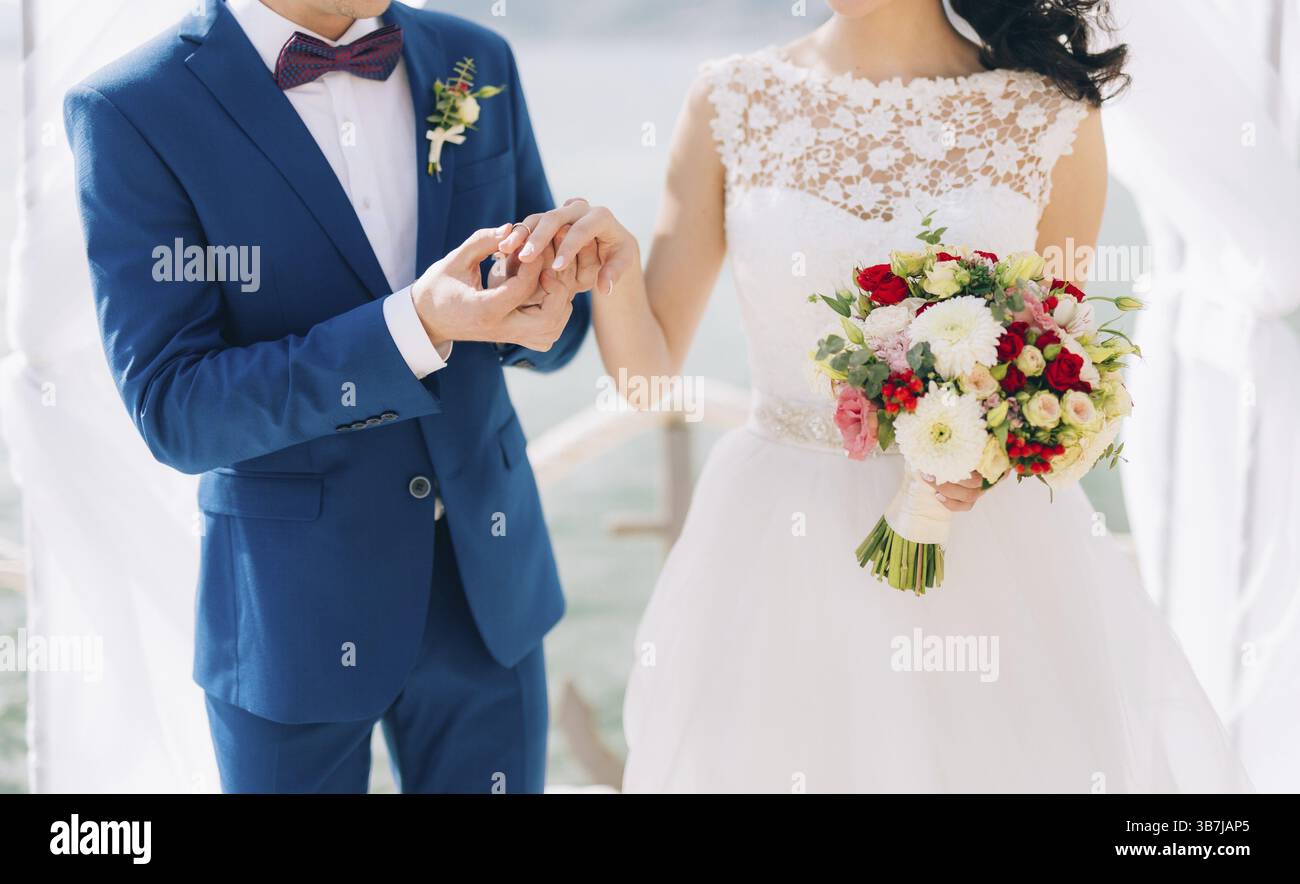 Lo sposo indossa un anello al dito della sposa durante una cerimonia nuziale. Matrimonio in Montenegro Foto Stock